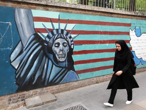 An Iranian woman walks past a mural on the wall of the former U.S. embassy in the Iranian capital Tehran on May 8, 2018.