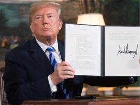 TOPSHOT - US President Donald Trump signs a document reinstating sanctions against Iran after announcing the US withdrawal from the Iran Nuclear deal, in the Diplomatic Reception Room at the White House in Washington, DC, on May 8, 2018.