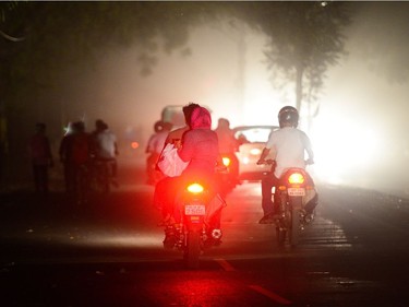 People dive scooters during a dust storm in Allahabad on May 13, 2018.