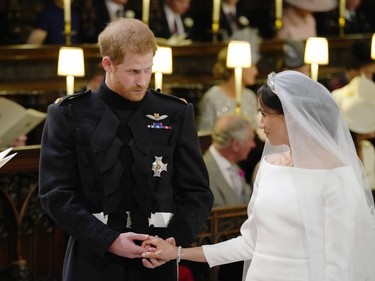 Britain's Prince Harry, Duke of Sussex (L) and US fiancee of Britain's Prince Harry Meghan Markle stand together hand in hand at the High Altar during their wedding ceremony in St George's Chapel, Windsor Castle, in Windsor, on May 19, 2018.