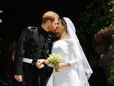 Britain's Prince Harry, Duke of Sussex kisses his wife Meghan, Duchess of Sussex as they leave from the West Door of St George's Chapel, Windsor Castle, in Windsor, on May 19, 2018 after their wedding ceremony.