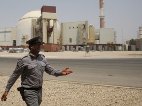 FILE - In this Aug. 21, 2010 file photo, an Iranian security official directs media at the Bushehr nuclear power plant, with the reactor building seen in the background, just outside the southern city of Bushehr, Iran. Iran's nuclear deal with world powers faces its biggest diplomatic challenge yet as President Donald Trump appears poised to withdraw the U.S. from the accord.