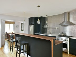 The dark cabinetry in this renovation by Moneca Kaiser Design Build serves to ground the space, allowing the wooden slab counter and stainless-steel metal mosaic tile backsplash to pop. The project was a finalist in the Housing Design Awards last fall.