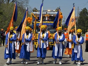 Members of the Sikh community carry flags in the Khalsa Day parade as it makes its way down Park Road North on Sunday May 13, 2018 in Brantford, Ontario.