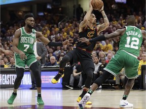 Cleveland Cavaliers' George Hill (3) looks to pass between Boston Celtics' Terry Rozier (12) and Jaylen Brown (7) in the first half of Game 3 of the NBA basketball Eastern Conference finals, Saturday, May 19, 2018, in Cleveland.
