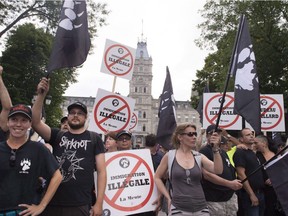 Demonstrators of a right wing group, "La Meute" demonstrate in silence in front of the legislature, Sunday, August 20, 2017 in Quebec City. Quebec City police say they've arrested two people in connection with an August demonstration that saw protesters clash with riot police.