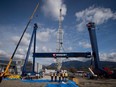 Workers watch as the main girder of a new 300-tonne gantry crane is lifted into place at Seaspan Vancouver Shipyards in North Vancouver, B.C., on Wednesday April 2, 2014.
