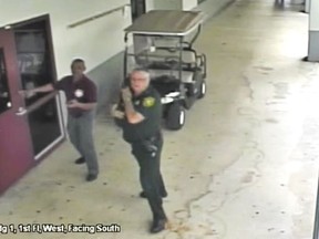 This Feb. 14, 2018 frame from security video provided by the Broward County Sheriff's Office shows deputy Scot Peterson, right, outside Marjory Stoneman Douglas High School in Parkland, Fla.