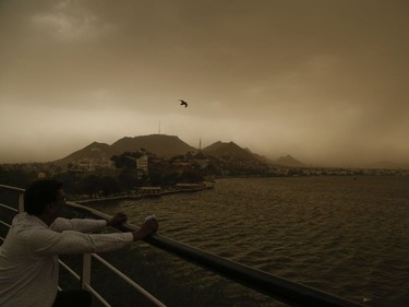 A man watches and a bird flies as a dust storm envelopes the Ana Sagar Lake in Ajmer, Rajasthan, India, Monday, May 14, 2018. A day earlier, powerful winds and rainstorms swept across a crowded swath of northern India, demolishing houses, uprooting trees and killing dozens of people.