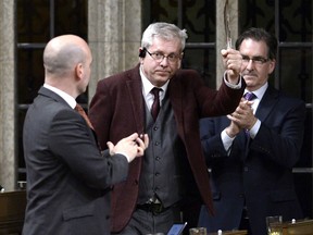 NDP MP Charlie Angus holds a feather as he rises to vote in favour of the NDP's motion calling on the House of Commons to officially ask the Pope to apologize to residential school survivors, on Parliament Hill in Ottawa on Tuesday, May 1, 2018.