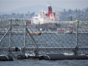 A oil tanker passes a floating chain link fence topped with razor wire in at the Kinder Morgan marine terminal in Burrard Inlet just outside of metro Vancouver, B.C., Tuesday, May, 1, 2018.