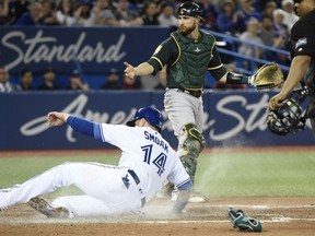 Toronto Blue Jays first baseman Justin Smoak (14) slides into home plate to score a run as Oakland Athletics catcher Jonathan Lucroy (21) looks on during fifth inning AL baseball action in Toronto on Thursday, May 17, 2018.