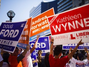People hold signs ahead of the Ontario Elections Leaders debate at the CBC building in Toronto on Sunday, May 27, 2018.