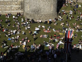 People relax on a grassy bank outside Windsor Castle after Prince Harry and Meghan Markle's wedding ceremony at St. George's Chapel in Windsor, near London, England, Saturday, May 19, 2018.