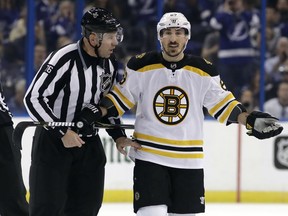 Boston Bruins left wing Brad Marchand (63) is escorted off the ice by linesman Michel Cormier (76) after taking a penalty against the Tampa Bay Lightning during the first period of Game 5 of an NHL second-round hockey playoff series Sunday, May 6, 2018, in Tampa, Fla.