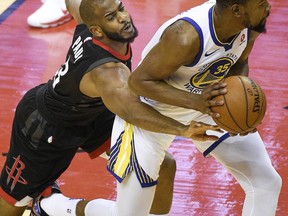 Houston Rockets guard Chris Paul, left, reaches for the ball held by Golden State Warriors forward Kevin Durant during the first half of Game 2 of the NBA basketball playoffs Western Conference finals Wednesday, May 16, 2018, in Houston.