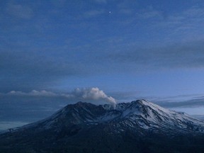 FILE - In this March 9, 2005 file photo, Mount St. Helens emits a small, steady cloud of steam at dusk in Washington state. The 2018 eruption of the Kilauea volcano in Hawaii has geologic experts along the West Coast warily eyeing the volcanic peaks in Washington, Oregon and California, including St. Helens, that are part of the Pacific Ocean's ring of fire.