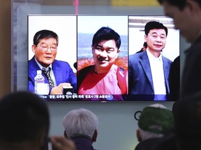 In this May 3, 2018 photo, people watch a TV news report on screen, showing portraits of three Americans, Kim Dong Chul, left, Tony Kim and Kim Hak Song, right, detained in the North Korea, at the Seoul Railway Station in Seoul, South Korea.