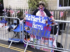 American royal fan Donna Werner, and who has come over to Britain specially for the upcoming royal wedding of Britain's Prince Harry and Meghan Markle, shows off her placards in her position along the carriage route in Windsor, England, Wednesday, May 16, 2018. Preparations continue in Windsor ahead of the royal wedding of Britain's Prince Harry and Meghan Markle Saturday May 19, which includes a 30 minute carriage route taking the couple round the town to wave to the crowds, some of whom are already taking up positions.