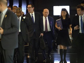 In this May 4, 2018 photo, U.S. Treasury Secretary Steven Mnuchin, center left, and Commerce Secretary Wilbur Ross, center right, leave their hotel in Beijing for trade negotiations with Chinese officials. In a looming trade war between the world's two largest economies, American companies in China may have a bull's-eye on their backs.