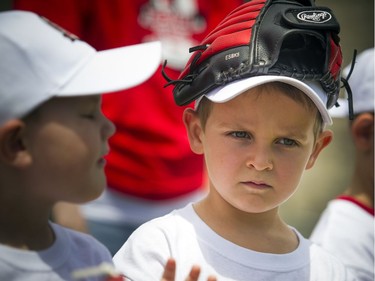 National Little League week kicked off with two teams coming together for a game of T-Ball on the lawn of Parliament Hill Sunday June 10, 2018. Willian Chenier wears his glove on his hat during the speeches prior to the game.   Ashley Fraser/Postmedia