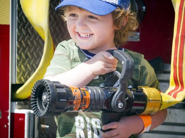 Two and a half year old Jack Doyle holds onto a fire hose as he was sitting on the back of a fire truck at the Touch A Truck event at Lincoln Fields Shopping Centre Sunday June 10, 2018.