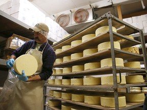 A worker places wheels of cheese on a wooden racks in a cooler at Vella Cheese on June 10, 2014 in Sonoma, California.