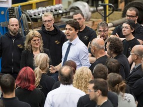 Prime Minister Justin Trudeau speaks to machine shop workers during a campaign visit with candidate Lina Boivin, left, Thursday, June 14, 2018 in Saguenay, Que.