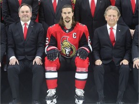 Erik Karlsson sits between general manager Pierre Dorion, left, and Senators owner Eugene Melnyk, right, for the official team photo on March 7.