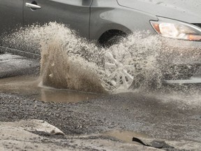 A car hits a pothole on St. Laurent Boulevard near Donald Street in February. Errol McGihon/Postmedia