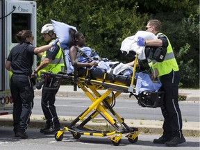 Paramedics transport a young woman into an ambulance at the scene of a two vehicle crash at the intersection of Hunt Club Road and Paul Benoit Driveway. June 26, 2018.