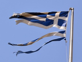 A ripped Greek national flag flutters in the wind.