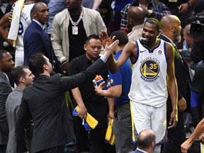 Warriors star Kevin Durant high-fives a fan as he leaves the court in the latter part of the fourth quarter on Friday night with victory against the Cavaliers assured.