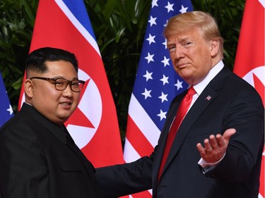 TOPSHOT - US President Donald Trump (R) gestures as he meets with North Korea's leader Kim Jong Un (L) at the start of their historic US-North Korea summit, at the Capella Hotel on Sentosa island in Singapore on June 12, 2018. - Donald Trump and Kim Jong Un have become on June 12 the first sitting US and North Korean leaders to meet, shake hands and negotiate to end a decades-old nuclear stand-off.