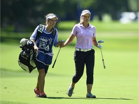 Brooke Henderson exchanges clubs with her sister and caddy, Brittany Henderson, on the ninth hole during Friday's round.