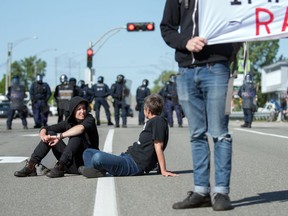 Protesters sit in front of riot police during a demonstration in Quebec City on June 8, 2018, as the G7 Summits gets underway.