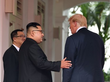 TOPSHOT - North Korea's leader Kim Jong Un (C) gestures as he meets with US President Donald Trump (R) at the start of their historic US-North Korea summit, at the Capella Hotel on Sentosa island in Singapore on June 12, 2018. Donald Trump and Kim Jong Un have become on June 12 the first sitting US and North Korean leaders to meet, shake hands and negotiate to end a decades-old nuclear stand-off.