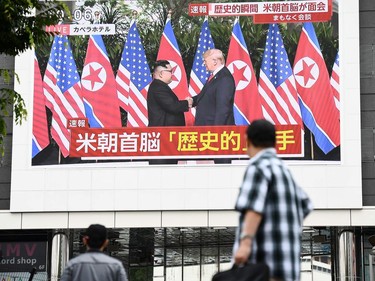 Pedestrians look at a screen displaying live news of meeting between North Korean leader Kim Jong Un and US President Donald Trump, in Tokyo on June 12, 2018. Donald Trump and Kim Jong Un have become on June 12 the first sitting US and North Korean leaders to meet, shake hands and negotiate to end a decades-old nuclear stand-off.