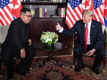 US President Donald Trump (R) gives a thumbs up as he sits down with North Korea's leader Kim Jong Un (L) for their historic US-North Korea summit, at the Capella Hotel on Sentosa island in Singapore on June 12, 2018. Donald Trump and Kim Jong Un have become on June 12 the first sitting US and North Korean leaders to meet, shake hands and negotiate to end a decades-old nuclear stand-off.