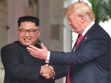 US President Donald Trump (R) shakes hands with North Korea's leader Kim Jong Un as they meet at the start of their historic US-North Korea summit, at the Capella Hotel on Sentosa island in Singapore on June 12, 2018. Donald Trump and Kim Jong Un have become on June 12 the first sitting US and North Korean leaders to meet, shake hands and negotiate to end a decades-old nuclear stand-off.
