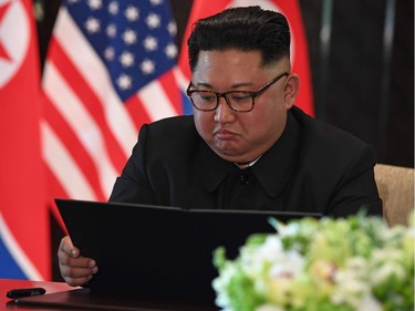 TOPSHOT - North Korea's leader Kim Jong Un looks at his document at a signing ceremony with US President Donald Trump (not pictured) during their historic US-North Korea summit, at the Capella Hotel on Sentosa island in Singapore on June 12, 2018.  Donald Trump and Kim Jong Un became on June 12 the first sitting US and North Korean leaders to meet, shake hands and negotiate to end a decades-old nuclear stand-off.