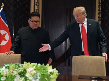 US President Donald Trump (R) gestures as he and North Korea's leader Kim Jong Un arrive for a signing ceremony during their historic US-North Korea summit, at the Capella Hotel on Sentosa island in Singapore on June 12, 2018.  Donald Trump and Kim Jong Un became on June 12 the first sitting US and North Korean leaders to meet, shake hands and negotiate to end a decades-old nuclear stand-off.
