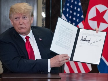 TOPSHOT - US President Donald Trump holds up a document signed by him and North Korea's leader Kim Jong Un following a signing ceremony during their historic US-North Korea summit, at the Capella Hotel on Sentosa island in Singapore on June 12, 2018.  Donald Trump and Kim Jong Un became on June 12 the first sitting US and North Korean leaders to meet, shake hands and negotiate to end a decades-old nuclear stand-off.