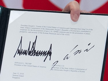 The signatures of U.S. President Donald Trump (L) and North Korea's leader Kim Jong Un (R) are seen on a document held up by Trump following a signing ceremony during their historic U.S.-North Korea summit, at the Capella Hotel on Sentosa island in Singapore on June 12, 2018.