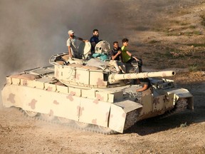 Syrian rebel fighters ride a tank in Daraa, southwestern Syria, on June 23, 2018.