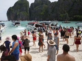 Tourists enjoy the beach on Maya Bay, Phi Phi Leh island in Krabi province, Thailand, Thursday, May 31, 2018. The popular tourist destination of Maya Bay in the Andaman Sea will close to tourists for four months from Friday to give its coral reefs and sea life a chance to recover from an onslaught that began nearly two decades ago.