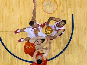 Phil Scrubb, top right, and Canadian teammate Dwight Powell vie for a rebound against China's Jinqin Hu (21) and Junfei Ren, bottom, during a game in Vancouver on June 22.