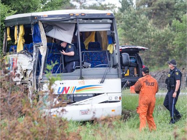 Police investigators on scene of the bus involved in the crash on the 401 west of Prescott. Photo by Wayne Cuddington/ Postmedia