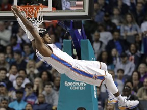 Paul George hangs from the rim after a dunk in an Oklahoma City Thunder game against the Charlotte Hornets in January.
