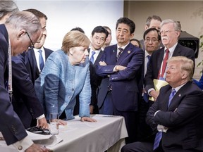 In this photo made available by the German Federal Government, German Chancellor Angela Merkel, center, speaks with U.S. President Donald Trump, seated at right, during the G7 Leaders Summit in La Malbaie, Quebec, Canada, on Saturday, June 9, 2018.